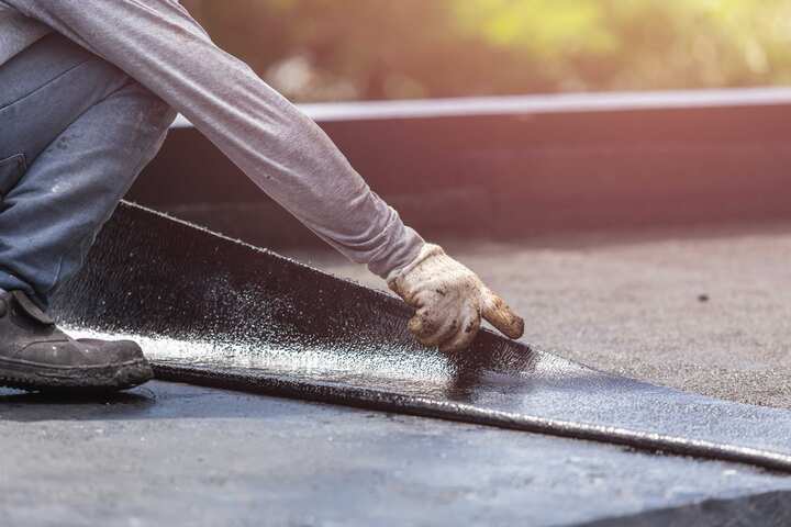 A contractor waterproofs a roof.